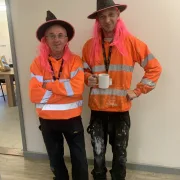 Harry with handyman Lia, both in high vis jackets and witches hats for October