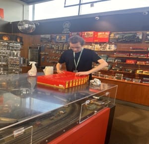 Tom volunteering in the shop and tidying the stock on shelves 